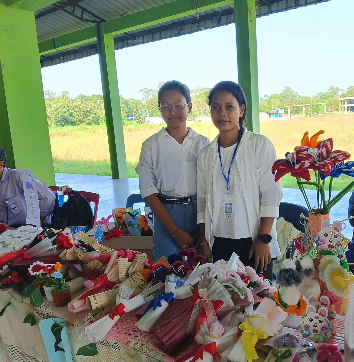 Two students behind handmade flower bouquets and keychains