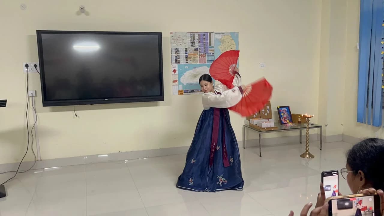 A dancer in hanbok performing a Korean fan dance
